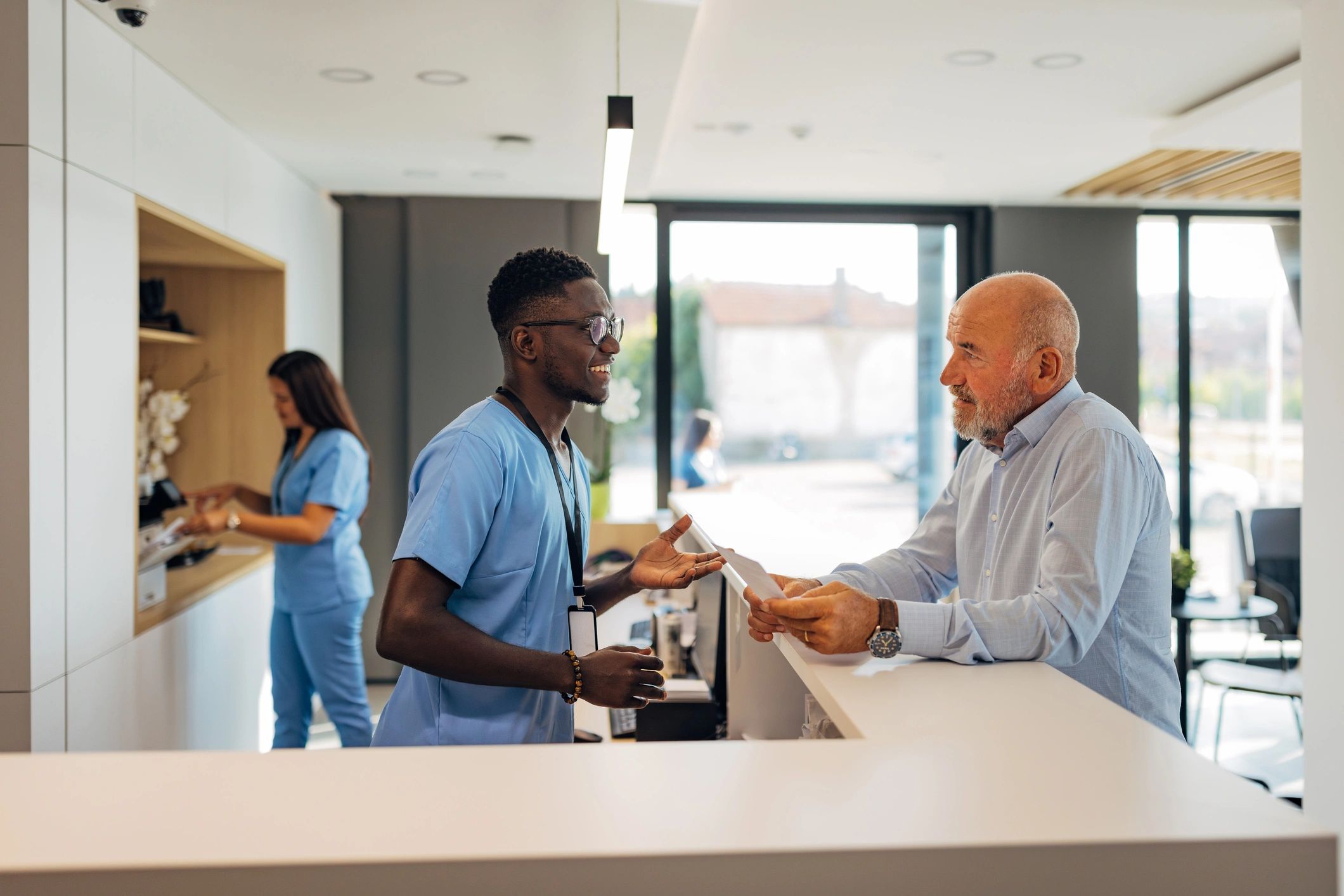 Clinic receptionist welcoming a senior patient at the reception desk
